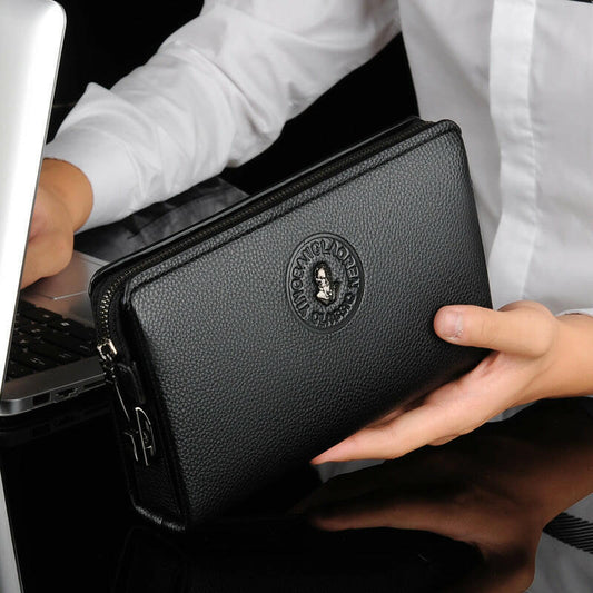 Black men's business casual leather clutch with zipper and embossed logo, held by a person in white shirt near a laptop